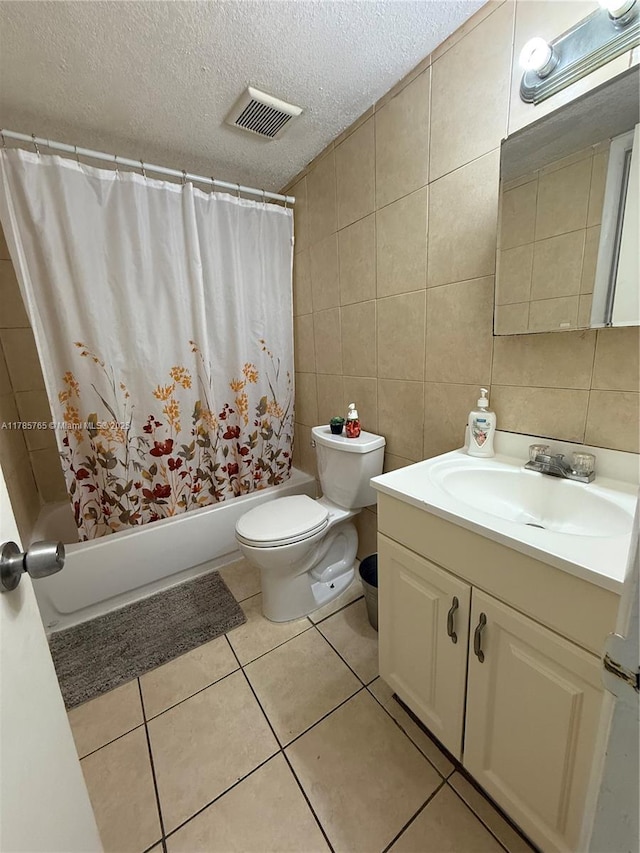 full bath with tile walls, shower / bath combo with shower curtain, toilet, visible vents, and a textured ceiling