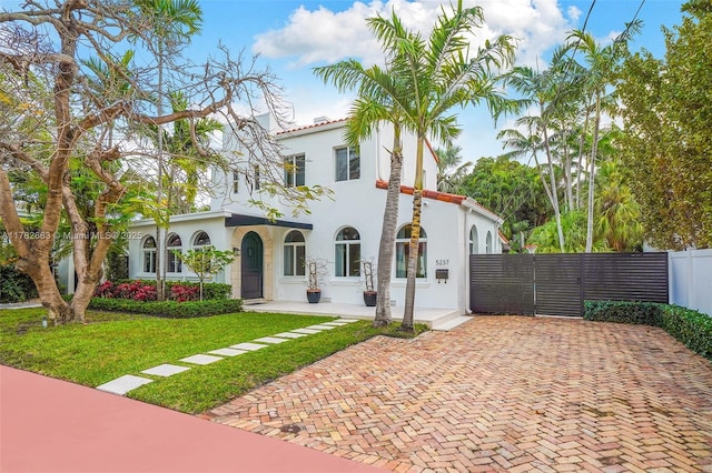 mediterranean / spanish-style home featuring stucco siding, fence, a tiled roof, and a front yard