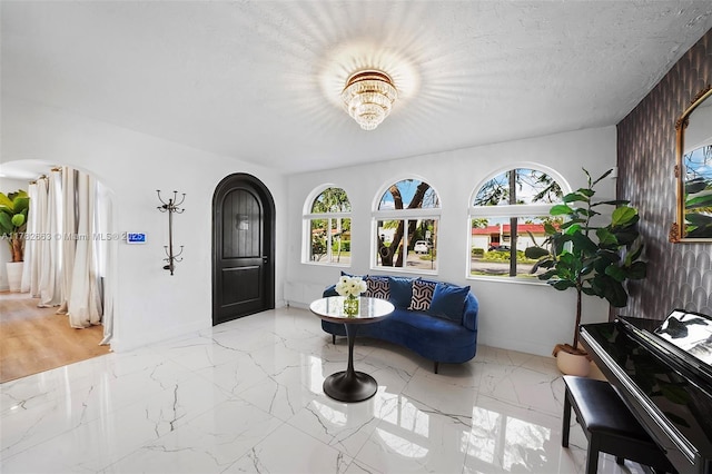 foyer entrance with arched walkways, marble finish floor, baseboards, and an inviting chandelier