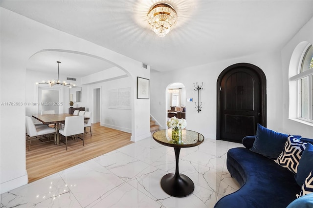 living area featuring arched walkways, an inviting chandelier, stairs, and visible vents