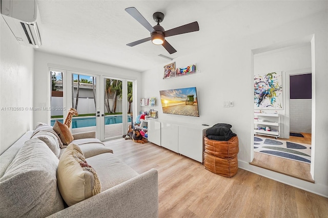 living room with ceiling fan, wood finished floors, and a wall unit AC