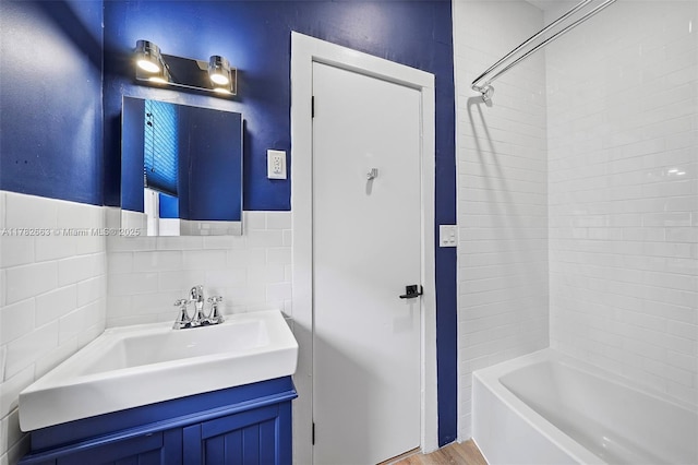 full bath with tile walls, vanity, and bathtub / shower combination