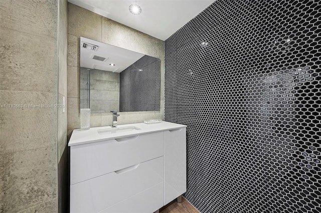 bathroom featuring tile walls, visible vents, vanity, and tiled shower