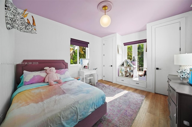 bedroom with multiple windows and light wood-type flooring