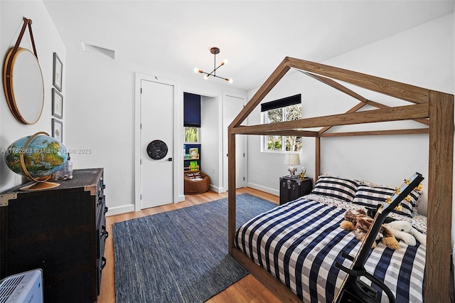bedroom with baseboards, a notable chandelier, and wood finished floors