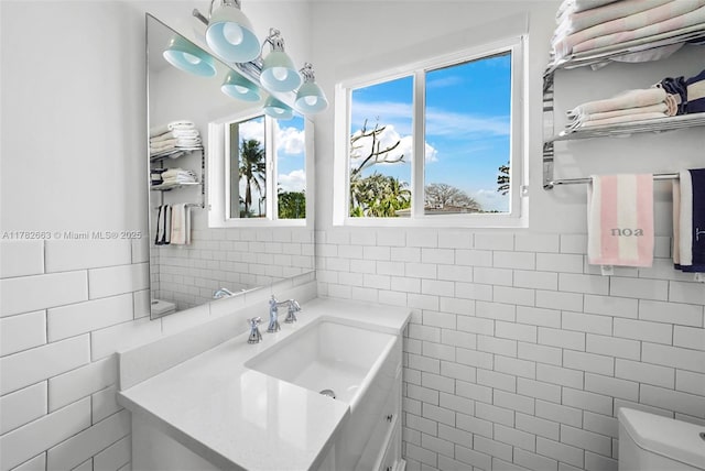 half bathroom with tile walls, plenty of natural light, vanity, and toilet