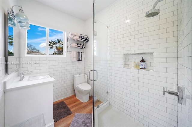 full bath featuring toilet, tile walls, wood finished floors, a shower stall, and vanity
