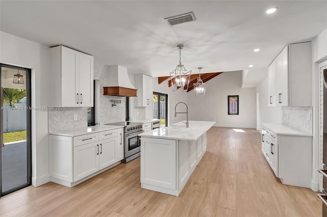kitchen with visible vents, custom exhaust hood, light wood-style floors, decorative backsplash, and electric stove