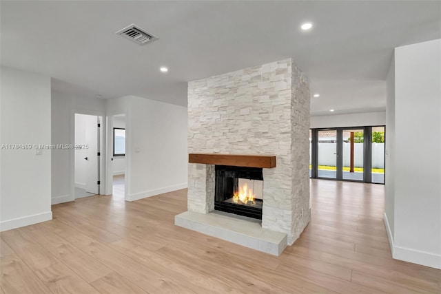 unfurnished living room with light wood-style floors, a fireplace, baseboards, visible vents, and recessed lighting