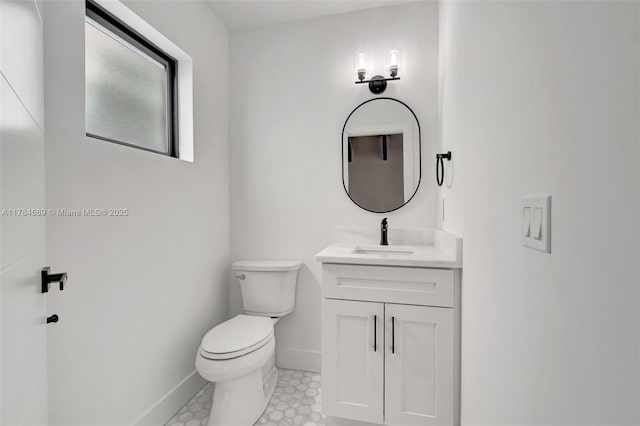 bathroom with toilet, vanity, and baseboards