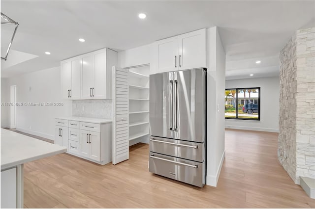 kitchen featuring baseboards, white cabinetry, light wood-type flooring, and freestanding refrigerator