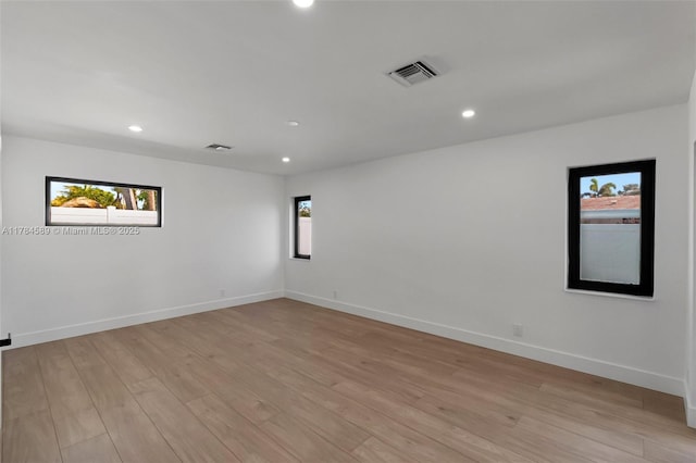 spare room with baseboards, light wood-style flooring, visible vents, and recessed lighting