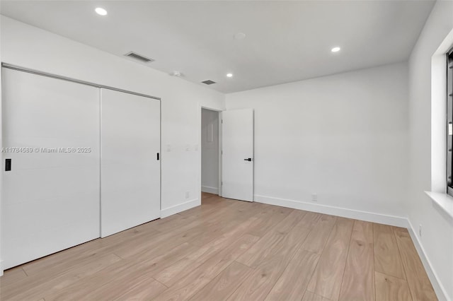 unfurnished bedroom featuring baseboards, light wood-style floors, and visible vents