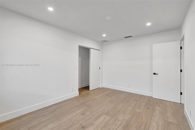 empty room with light wood finished floors, baseboards, and recessed lighting