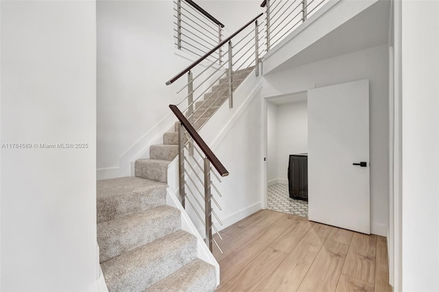 stairway with a high ceiling and wood finished floors