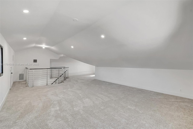 additional living space with vaulted ceiling, carpet flooring, visible vents, and baseboards
