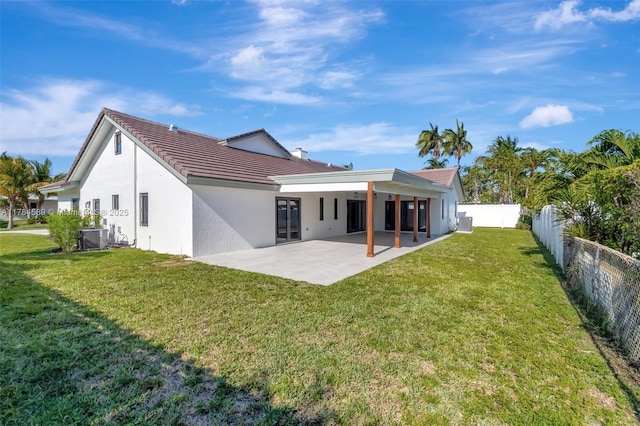 back of property with a tiled roof, fence private yard, a yard, a patio, and stucco siding