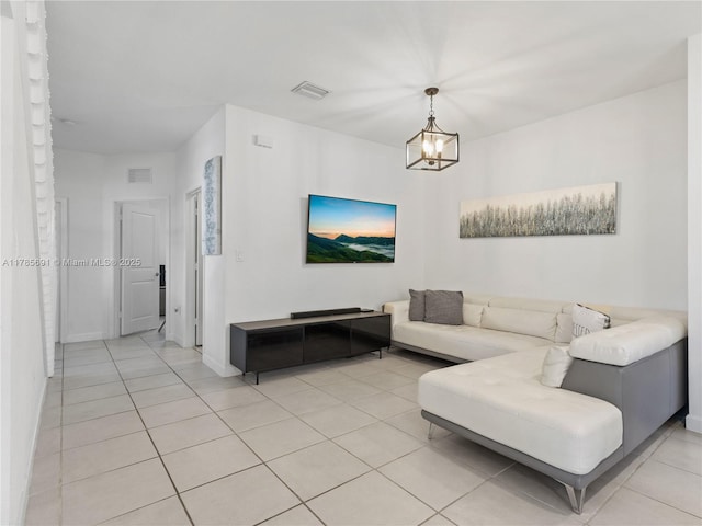 living area featuring light tile patterned flooring, a chandelier, visible vents, and baseboards