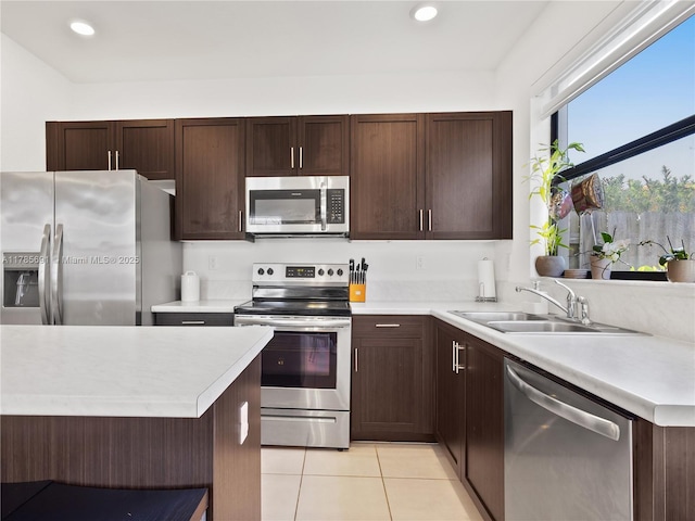 kitchen featuring light tile patterned floors, appliances with stainless steel finishes, a sink, and light countertops