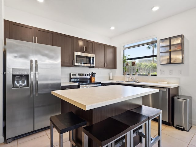 kitchen featuring light countertops, dark brown cabinets, a sink, light tile patterned floors, and appliances with stainless steel finishes