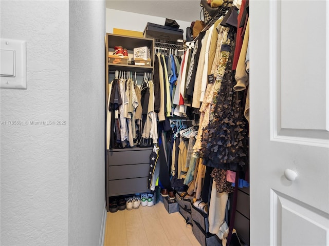 walk in closet with wood finished floors