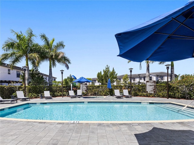 community pool featuring fence and a patio