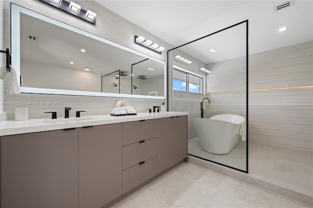 full bath featuring tile walls, double vanity, a soaking tub, and walk in shower