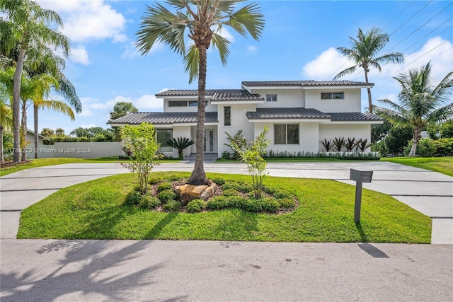 view of front facade with curved driveway, stucco siding, and a front lawn