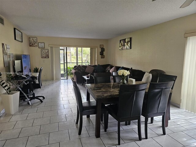 dining area featuring a textured ceiling and light tile patterned floors