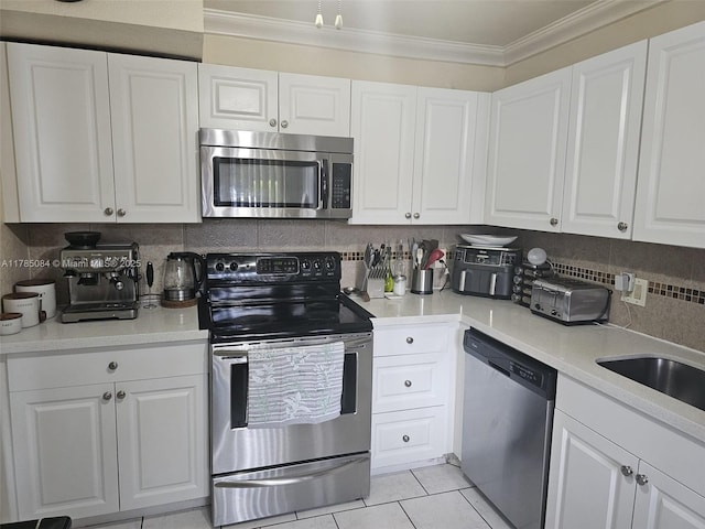 kitchen with backsplash, appliances with stainless steel finishes, crown molding, and white cabinetry