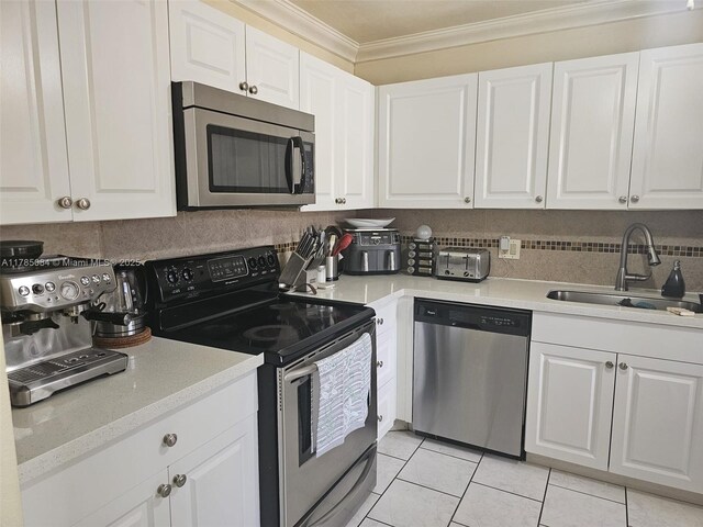 kitchen featuring white cabinets, crown molding, stainless steel appliances, and a sink