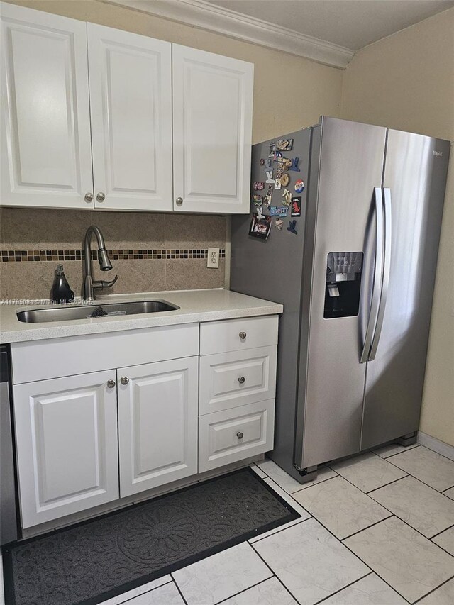 kitchen featuring stainless steel fridge, decorative backsplash, ornamental molding, and a sink