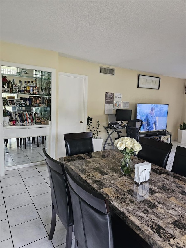 dining space with visible vents, a textured ceiling, and light tile patterned flooring