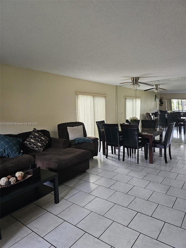 living room with ceiling fan, a textured ceiling, and light tile patterned floors
