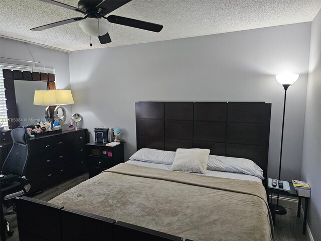 bedroom featuring wood finished floors, a textured ceiling, and a ceiling fan