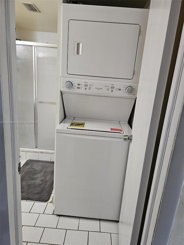 laundry room with tile patterned floors, stacked washer and clothes dryer, and laundry area