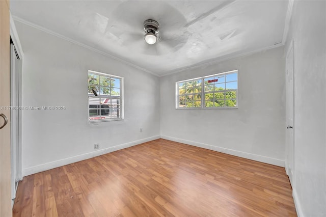 spare room featuring a ceiling fan, baseboards, crown molding, and light wood-style floors