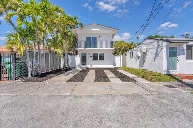 view of front of home featuring fence, concrete driveway, a balcony, and stucco siding