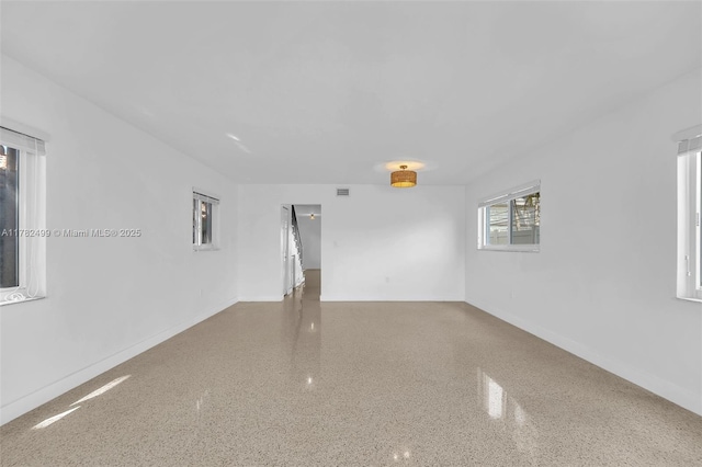 empty room featuring speckled floor, baseboards, and visible vents