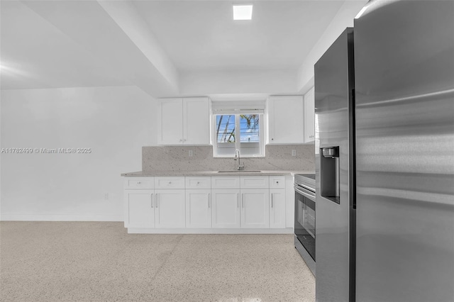 kitchen with stainless steel appliances, backsplash, a sink, baseboards, and white cabinetry