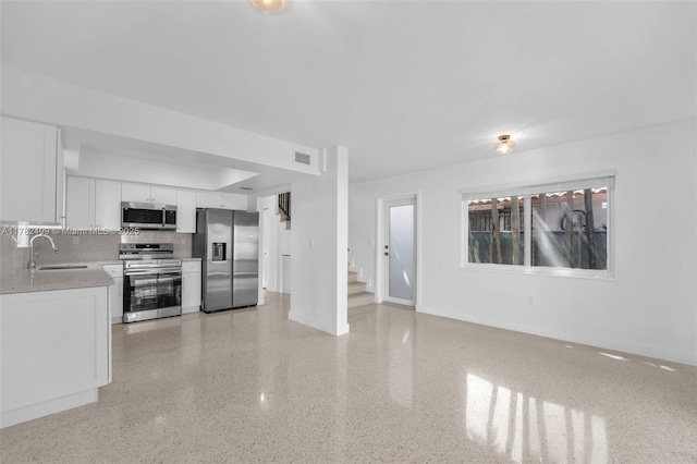 kitchen with a sink, white cabinetry, baseboards, appliances with stainless steel finishes, and visible vents