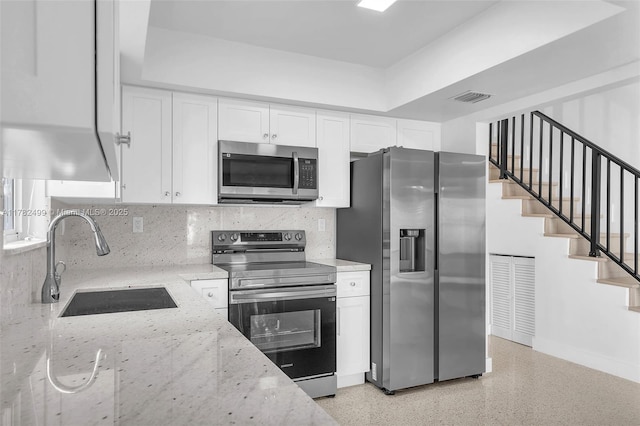 kitchen featuring white cabinetry, light stone countertops, stainless steel appliances, and a sink