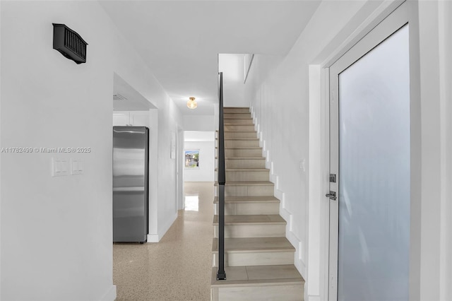 staircase with baseboards and speckled floor