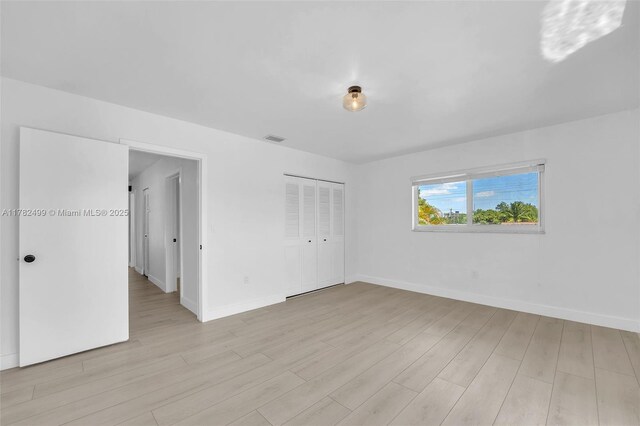 unfurnished bedroom featuring baseboards, visible vents, and light wood-style floors
