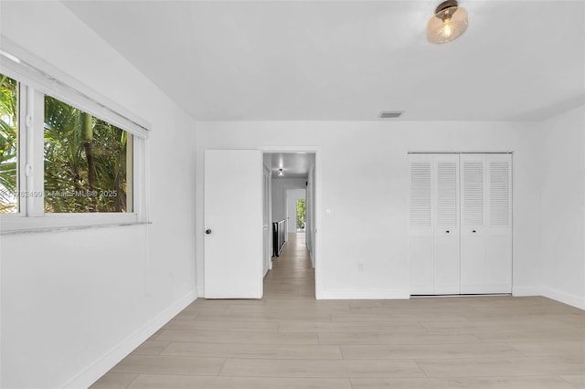 unfurnished bedroom with light wood finished floors, baseboards, visible vents, and multiple windows