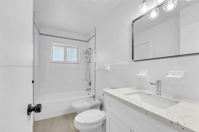 full bath featuring toilet, tile walls, wood finished floors, vanity, and tub / shower combination