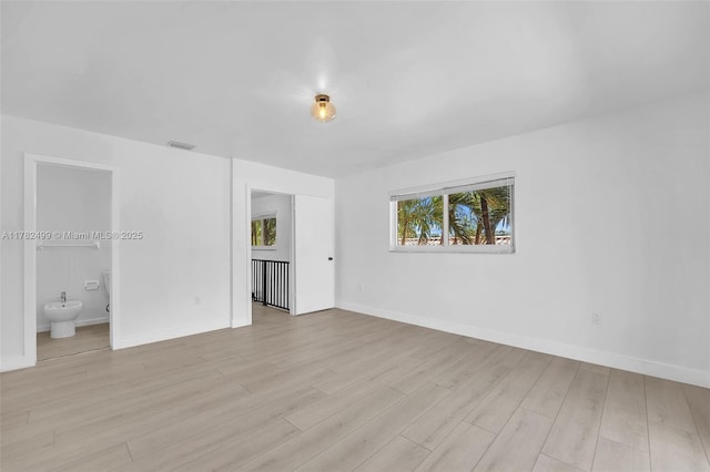 unfurnished bedroom featuring light wood-type flooring, visible vents, baseboards, and connected bathroom