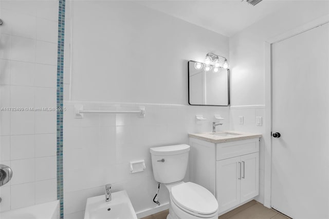 full bathroom featuring tile walls, wainscoting, vanity, and toilet