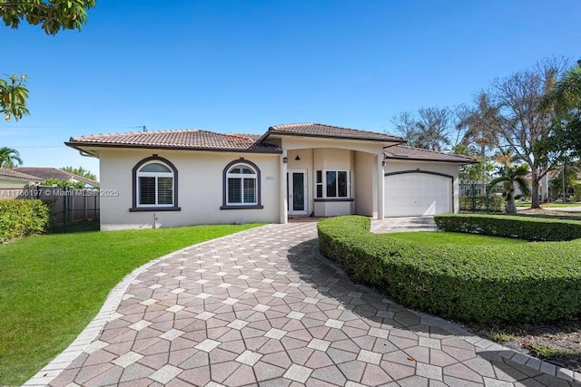 view of front of home featuring fence, a front lawn, stucco siding, a tile roof, and a garage