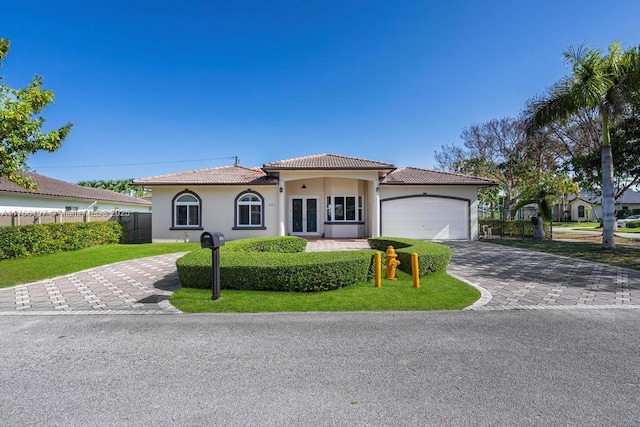 view of front of house with fence, stucco siding, a tile roof, driveway, and a garage